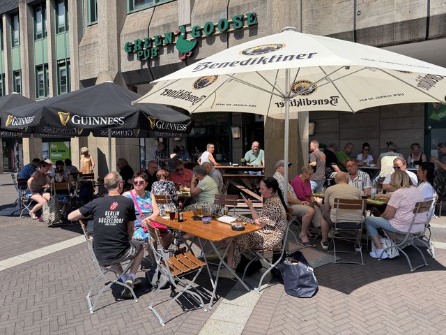 Außenbereich des Green Goose Pub am Rathausplatz mit Sonnenschirmen und Gästen
